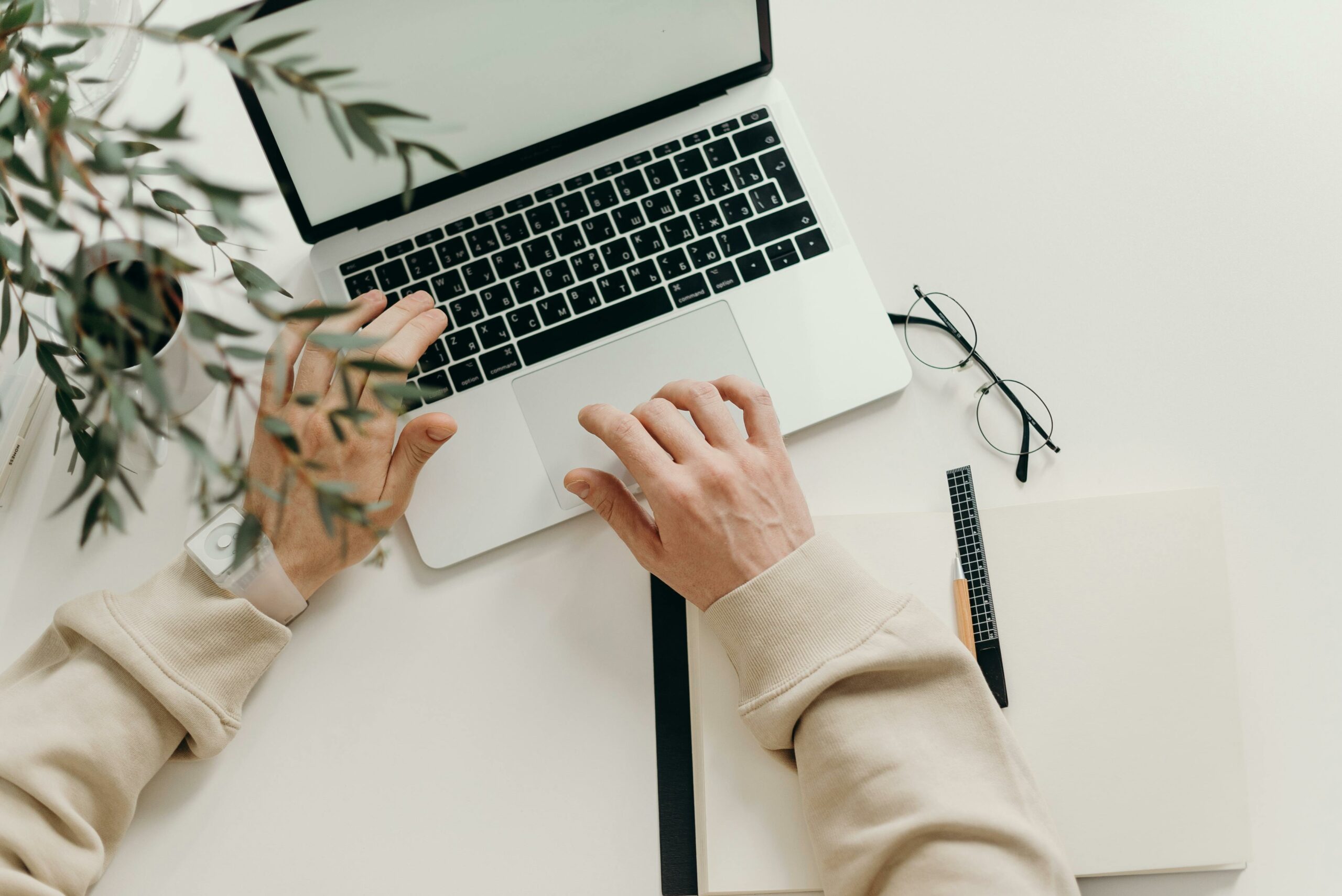 Mains sur le clavier d'un ordinateur portable, sur un bureau blanc